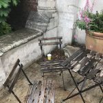 A small rustic table and chairs on a patio, and a Styrofoam cup beneath it all.